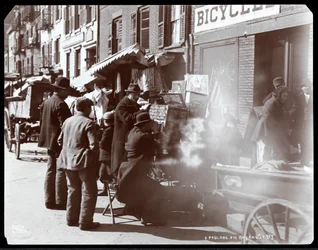 1898年にニューヨークのベヤードストリートで、ビューボックスにエキゾチックな場所の写真を表示している人を含む、露店の様子（銀ゼラチンプリント）