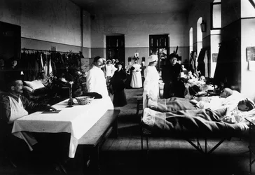 戦傷病者、医師、赤十字の看護師、訪問者がいる病院の装飾されたサロン（モノクロ写真
