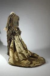 イブニング・ドレス、1884年頃（背面斜視図）。シルクサテン、カットベルベット、レース、シルク糸のタッセルとフリンジ。チャールズ・フレデリック・ワース、フランス。