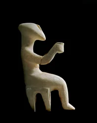 キクラデス諸島のアート。「スツールに座る置物」 黄土色の象嵌を施した大理石の偶像。キクラデス文明（～3200年頃～2000年頃） 太陽。15.2 cm アテネ国立考古学博物館 (inv. 3910)