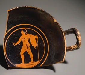Pteriu PavesによるKylix、若い男性を描いた断片と碑文。グロッティ（トスカーナ州）の墓3から出土した赤像の土器。エトルリア文明、紀元前4世紀。