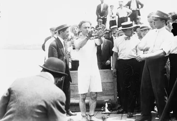 1912年にクレートに釘付けになり、ニューヨーク湾に降ろされる前に手錠をかけられているハリー・フーディーニ
