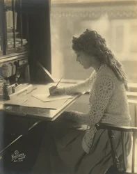 机に向かって書くメアリー・ピックフォード、1918年頃（白黒写真）