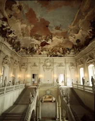 大階段と、ジョヴァンニ・バッティスタ（ジャンバッティスタ）・ティエポロ（1696-1770）が装飾した「五大陸の寓意」を表す天井の眺め。1753年 建築家ヨハン・バルタザール・ノイマン（1687-1753）が実現したヴュルツブルク（Wurzburg）の宮殿 ゲルマ