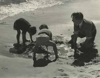 ビーチで砂遊びをする3人の子供たち。