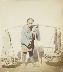 釣った魚を持つ漁師（手彩色のモノクロ写真