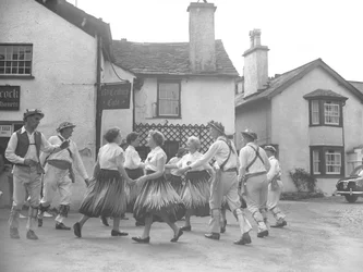 ホークスヘッドでダンスを踊る男女。背後に「15センチュリー・カフェ」の看板とオークショニア。