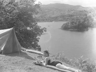 湖を背景に、水着を着てリロの上に横たわる若い女性の眺め。