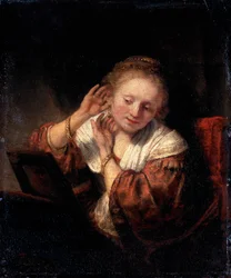 イヤリングを試す若い女性、1657年。