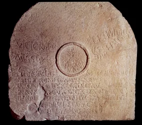 ローマ時代のアンティキテ：2人のアフリカ人殉教者の碑文が刻まれた奉納用テーブルストーン（メンサ）。キリスト教のシンボルであるクリスミーが表現されています。西暦300〜350年アルジェリア、Kherbet-oum-el-Ahdam出土。パリ、ルーヴル美術館