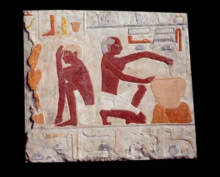 古代エジプトのアート：パンを焼く。一人がケーキのペーストを作り、もう一人がパンの型の焼き上がりを監視している。石灰岩（紀元前2500-2350年）第5王朝時代。パリ、ルーヴル美術館（Musee Du Louvre