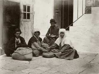 1867年にエルサレムの家の中庭で丸い石を使って小麦粉を挽いている女性