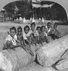 ヤシの丸太の上に座っているビルマの子供たち、ビルマ、1908年