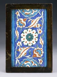 スクロールするパルメットと緑豊かなつるの間に中央の花頭があるイズニックボーダータイル、c.1570（セラミック）