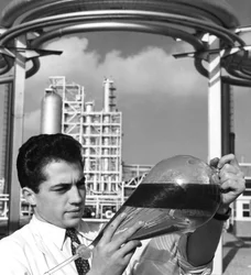 実験室の労働者が油の分離漏斗を保持している、ダンケルク製油所、フランス、1950年代