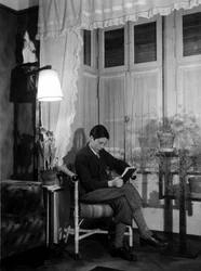 ブルジョア風のインテリアに座って本を読むティーンエイジャー。半ズボンにハイソックス。1915.歴史的写真、読書する女性、1915年頃