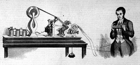 アメリカの発明家、サミュエル・フィンリー・ブリース・モース（1791～1872）が自分の電信機の横に写っている。19世紀の銅版画