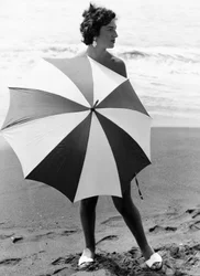 ビーチで傘をさす女性、1960年頃（モノクロ写真）