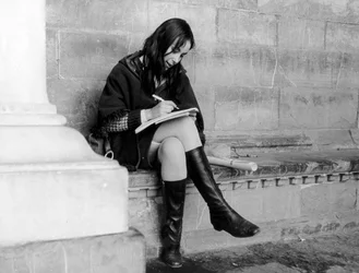 フィレンツェのロッジア・デル・ランツィの下で書き物をする若い女性、1965年頃（モノクロ写真）