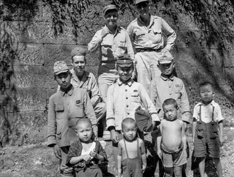 日本の降伏後、日本人の家族と一緒にポーズをとる米兵たち。
