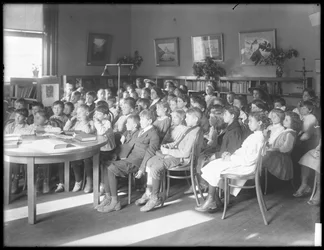 クイーンズ区公共図書館の正体不明の支部の読書室で座っている子供たち、1910年頃