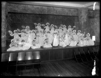 おそらくローマンカトリックの孤児の庇護、キングスブリッジ、ブロンクス、c.1911のファンがいる小さなステージでポーズをとった小さな女の子のグループ