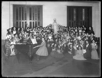 1911年頃、ブロンクスのキングスブリッジにあるローマカトリックの孤児の亡命場で、ピアノを弾いた楽譜の周りに集まった少女合唱団のグループの肖像画。