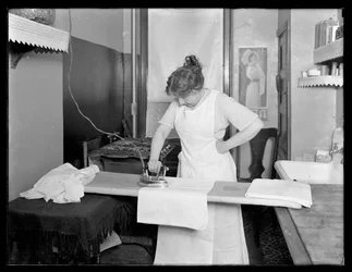電気アイロンの使用を示す正体不明の女性c.1913-14