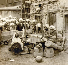 1901年頃、インド・カシミール地方のスリナガルで、毛糸のショールを紡ぎ、織っている様子（写真